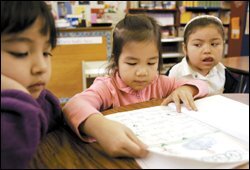 Kindergartner Christine Nguyen, center, reads for pre-K pupils Daphne Abad, left, and Belen Robeles during a visit to the Baldwin Academy library.