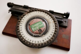 A Simplex-brand typewriter dated 1913. Index typewriters of this sort taught children the fundamentals of typing. One hand operates a pointer that selects a letter from the index, or wheel, while the other hand depresses a lever that moves the type to the paper.