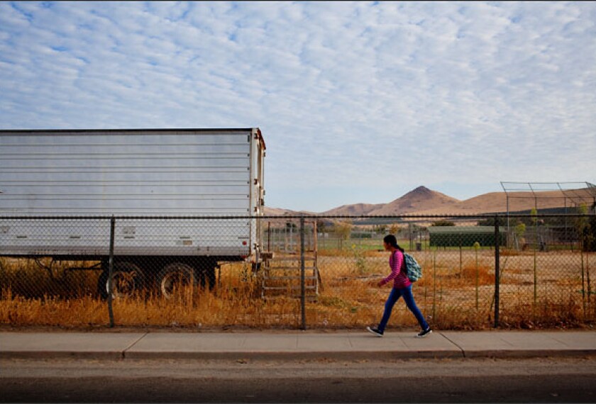 A student walks past trailers set up for additional construction at Lindsay High School in Lindsay, Calif., where the rural district has put in place an ambitious competency-based education system for all grades.
