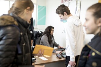 Burnsville senior Leslie Medina, center, helps students deposit money into their accounts at a Firefly Credit Union branch office that is located inside the school.