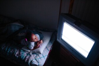 Light from a television illuminates Kimora Gantt, 8, as she unwinds after finishing her homework.