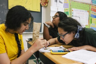 Elainie Alfonso, right, a 6th grader in the Paterson Academy for the Gifted and Talented, works on solving math problems in class with her fellow students.