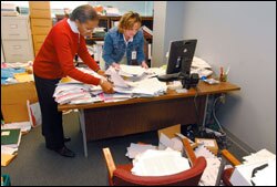 Indiana Department of Education employees Sharon Watts, left, an administrative assistant, and Kerry Hoffman, a consultant in the school assessment division, sort through a colleague's papers.