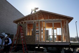 Sophomore Caleb Caraker, 16, attaches plywood sheathing to the roof of a tiny house on Friday, March 22, 2019 at Battle High School in Columbia, Mo. Students in a combined construction and geometry class are building a tiny house for a low-income family in the community.