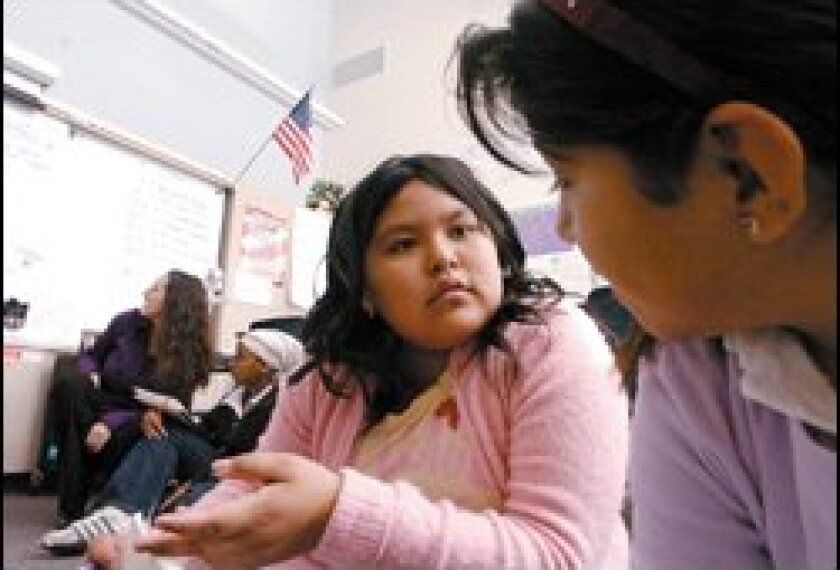 Erica Giles, center, discusses a math problem with Sandra Trujillo. Their teacher, Michelle Collins, at the whiteboard, presents fewer problems in more depth at Ibarra Elementary School in San Diego.