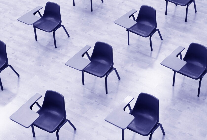 Image shows empty desks in a classroom.