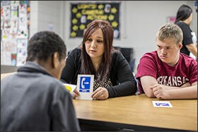 Paraprofessional Karla Castaneda works with 8th graders Charod Cohen, 13, and Luke Lowry, 14, right, on identifying signs in a special education classroom at Siloam Springs Middle School in Arkansas.