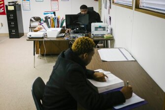Chrissell Rhone works at his desk while a student takes a GED preparatory exam at the Picayune Center for Alternative Education.