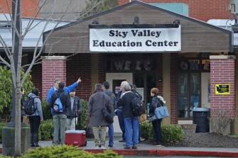 In this Jan. 4, 2019 photo, workers and other officials gather outside the Sky Valley Education Center school in Monroe, Wash., before going inside to collect samples for testing. The samples were tested for PCBs, or polychlorinated biphenyls, as well as dioxins and furans. A lawsuit filed on behalf of several families and teachers claims that officials failed to adequately respond to PCBs, or polychlorinated biphenyls, in the school.