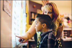 Teacher April Stenger helps kindergarten student Valentino Diego Torres, 5, order lunch using an interactive whiteboard at Minnehaha Elementary School.