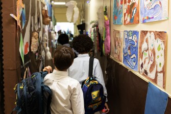 Students pass through a display of art projects between classes at the Odyssey School on March 30, 2023.