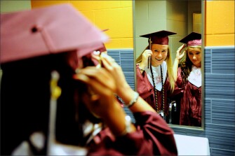 Friends Lauren Powell, left, and Ryleigh Fulcher fix their hats and hair in a mirror as they wait to file into the Ford Center in Evansville, Ind. for Henderson County High School’s 2014 Commencement.