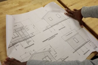 Carl Dement, woodworking and construction teacher, displays the plans for the tiny house on Friday, March 22, 2019 at Battle High School in Columbia, Mo. Students in a combined construction and geometry class are building a tiny house for a low-income family in the community.