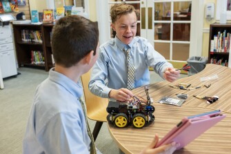 Students in the 7th grade class participate in Genius Hour where they can pitch and pursue a passion project over the course of the year. Here, Luke, 13, center, and Camden, 13, left, look over each others projects on March 30, 2023.