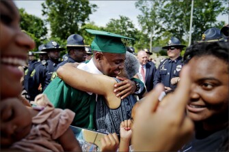 Hezekiah Jordan, left, son of fallen Griffin, Ga., police officer Kevin Jordan, is embraced by his grandmother, Lillie Colquitt, while surrounded by Griffin police officers after receiving his high school diploma. Authorities have said Officer Kevin Jordan was off-duty working an overnight shift as a security guard at a Waffle House restaurant when he was fatally shot during a fight with three people who were asked to leave the business. Jordan, 43, left behind seven children.
