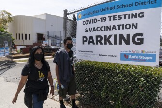 Parent Rosa Vargas and her son, 9th grade student Victor Loredo, 14, walk home after getting tested at a Los Angeles Unified School District COVID-19 testing and vaccination site in East Los Angeles on April 15, 2021. California will become the first state in the nation to require all teachers and school staff to get vaccinated or undergo weekly COVID-19 testing. The statewide vaccine mandate for K-12 educators comes as schools return from summer break amid growing concerns of the highly contagious delta variant. Democratic Gov. Gavin Newsom announced the new policy Wednesday, Aug. 11, 2021 as he visited a San Francisco Bay Area school that has already reopened after summer break.