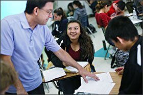 Gualter Moura, an AP Calculus teacher at Mission Bay High School in San Diego, helps Franci Arreola, center, with a math project. The San Diego school district is pushing to expand access to advanced courses for low-income students and students of color.
