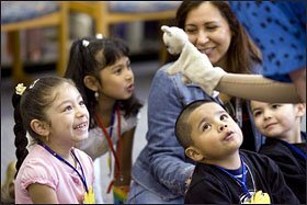 A smiling Yuriana Martinez, 5, left, and Carlos Siete, 6, second from right, watch as librarian Jane Hampton greets children with a hand puppet during a Head Start trip to the Tillicum, Wash., library.