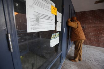 In this Feb. 4, 2019, photo, Steven Harris, a grandfather and former city council member, looks inside the abandoned John C. Clark Elementary and Middle School in Hartford, Conn. The school was closed in 2015 after toxic PCBs were found during a renovation. It is one of several Hartford public schools built during the era when PCBs were commonly used in school construction in caulk, floor adhesive and certain types of fluorescent light ballasts.