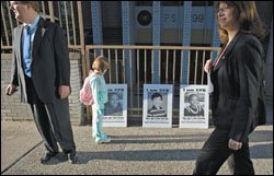 A girl pauses to look at photos of elementary students outside Public School 199 in New York City. The photos are part of a campaign to get more state education funding.