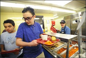 Nick Lethbridge, in striped shirt, gets lunch in the cafeteria at Martin Middle School in East Providence, R.I. Until this year, he rode a bus to school in Massachusetts.