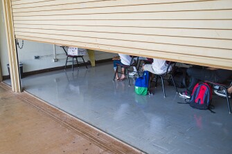 With the gate propped half way open to provide ventilation, class is held in a converted garage at Campbell High School, Monday, Aug. 3, 2015 in Ewa, Hawaii. Many public school classrooms across the Island are not equipped with AC, making it difficult for both teachers and students when the temperatures are high. In Hawaii, which has been experiencing record high temperatures, school officials are weighing whether it makes sense to have heat days, where they cancel school because it's simply too hot.