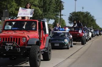 Kyle Nolan, left on the roof, holds a sign that reads “Mama, We Made It”, as she joins others in a neighborhood parade honoring 2020 student graduates from both J.J. Pearce and Richardson High Schools in Richardson, Texas, Saturday, May 9, 2020. The event was organized by a group of parents who asked neighborhood residents to come out and cheer on the local graduates whose traditional ceremonies were canceled due to COVID-19.