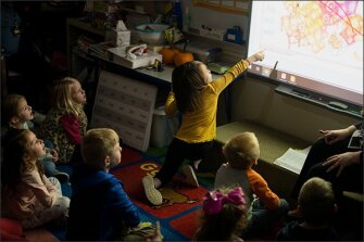 Ava Newton, a student in Ashley Palmer’s kindergarten class, points at the projector screen during a reading comprehension lesson.