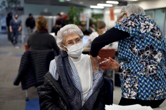 Mary Pitts of Anchorage gets a vaccine injection from nurse Jan Ilutsik, right. The Anchorage School District headquarters hosted a COVID-19 vaccine clinic in Anchorage, Alaska, on February 3, 2021.