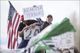 Hillcrest High School senior Ryler Hanosky, left, and junior Bret Gillespie, seen behind a flag associated with the alt-right, call for teachers to be armed during a counter-protest as classmates participate in a walkout to protest gun violence on March 14 in Idaho Falls, Idaho.