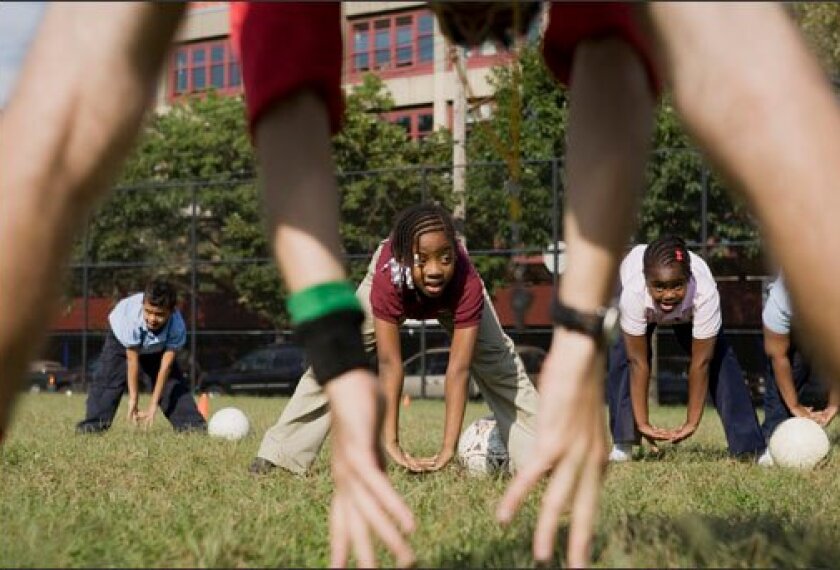 Nine-year-olds Deanna Dow, middle,Yarei Sanchez, left, and Krysalli Bloomfield, right, stretch before playing soccer at the UFT Charter School in Brooklyn on Sept. 17.