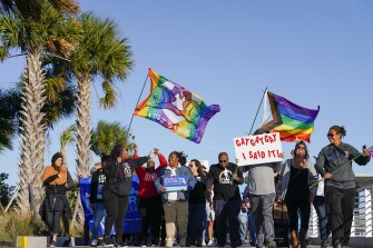 Marchers wave flags as they walk at the St. Pete Pier during a rally and march to protest against a bill dubbed by opponents as the "Don't Say Gay" bill on March 12, 2022, in St. Petersburg, Fla. Florida lawmakers have passed the bill, which forbids instruction on sexual orientation and gender identity in kindergarten through third grade. It now moves to the desk of Republican Gov. Ron DeSantis, who is expected to sign it into law.