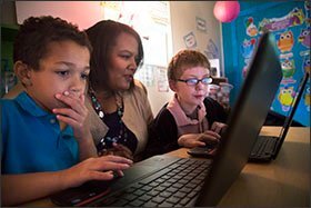 Rafranz Davis, the executive director of professional and digital learning for the Lufkin Independent School District in Texas, joins Dunbar Primary School students Aden Ligon, left, and Justice Trevino, while they learn coding skills and practice math.