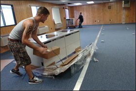 Trea Gautreaux, left, who works for a contractor with the Recovery School District, unpacks computer desks for a modular classroom.