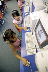 First graders Melissa Placencio, top, and Alejandra Arbizo work on their computer skills during class.