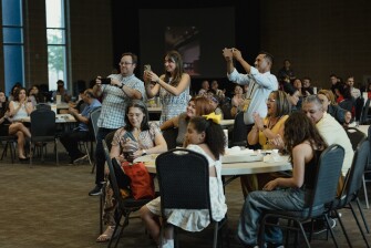 Matt Hinkle and Eva Valenzuela take photographs of Melody Hinkle during the awards dinner for the National Spanish Spelling Bee at the National Hispanic Cultural Center on July 12, 2025.