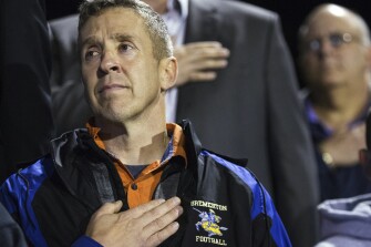 Bremerton assistant football coach Joe Kennedy, recently placed on administrative leave due to his prayers on the football field after games, listens to the national anthem from the stands at Memorial Stadium in Bremerton, Wash. on Thursday, Oct. 29, 2015.