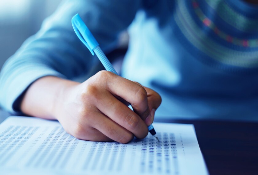 Close up of student holding a pencil and filling in answer sheet on a bubble test.