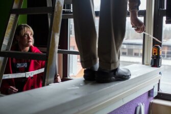 Shawna Sparks, parent at Collins Middle School in Fayette County, helps a local resident measure the shifting of a wall in a closed portion of the school’s building.