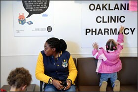 Mayah Miller, 3, right, spells out the words on a sign as she waits with her half-sister, Atalina Carter, to see a doctor for her wellness checkup.