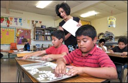 Trina Johnson, a teacher at Senath Elementary School in Missouri watches as students Roberto Chamberlain and David Pina work on an English assignment.
