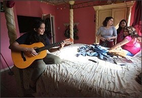 Betty Torres strums a guitar in her bedroom in Mission, Texas. Looking on, from left to right, are cousins Krystal Santillan and Alessandra Jaimes and Betty’s sister, Samantha, who is seated.