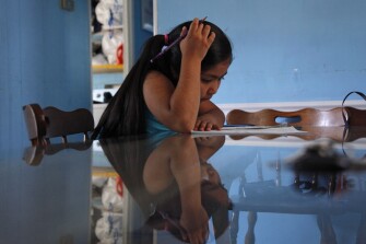 Ruby Pacheco works on homework inside her trailer home after school in Foley, Ala.