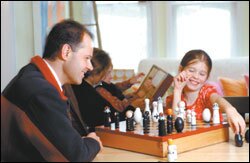 Watkins plays chess with his daughter, Emma, as his wife, Cath, and their son, Oliver, read a book in the family's house on the central New Jersey campus.