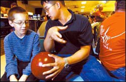 St. Lawrence senior Tam 'Tom' Nguyen shows Steven Andrews, 14, how to hold a bowling ball while volunteering at a Friday-night Special Olympics event.