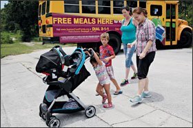 Nicole Deso, far right, and Allison Bass follow their children home after a stop at the lunch bus. The bus brings free meals in the summer to children in Pasco County, Fla.