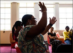 April Conaway, a 4th- and 5th-grade math teacher at Windsor Hills Elementary School in Baltimore, celebrates as she remembers a positive moment from her day during a Happy Teacher Revolution meeting. —Erin Irwin/Education Week