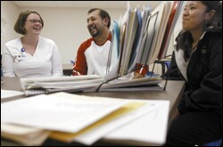 Paula Wood, left, a translator for the West Liberty school district, talks with Eliseo Tapia, center, and his daughter, Laura Rios, during a recent parent-teacher conference at West Liberty High School.