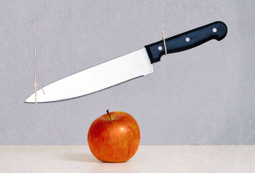 Sword of Damocles threat, risk concept, metaphor - large knife tied and suspended over an apple. Cuts to department of Education.