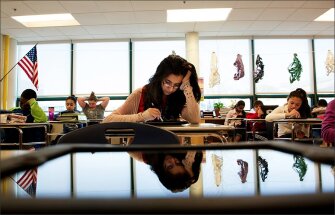 Seventh graders at Marshall Simonds Middle School in Burlington, Mass., including Nimra Mian, reflected here in an iPad, look at a practice PARCC test to gain familiarity with the format before a field test of exams tied to the common-core standards. The field tests for PARCC and Smarter Balanced began in March, marking an assessment experiment of unprecedented scope.